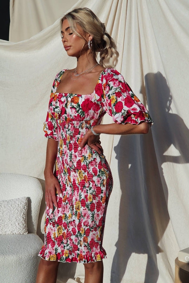 Model wearing Arabella Midi Dress, floral design with elastic sleeves and neckline, showcasing vibrant colors in a stylish fit.