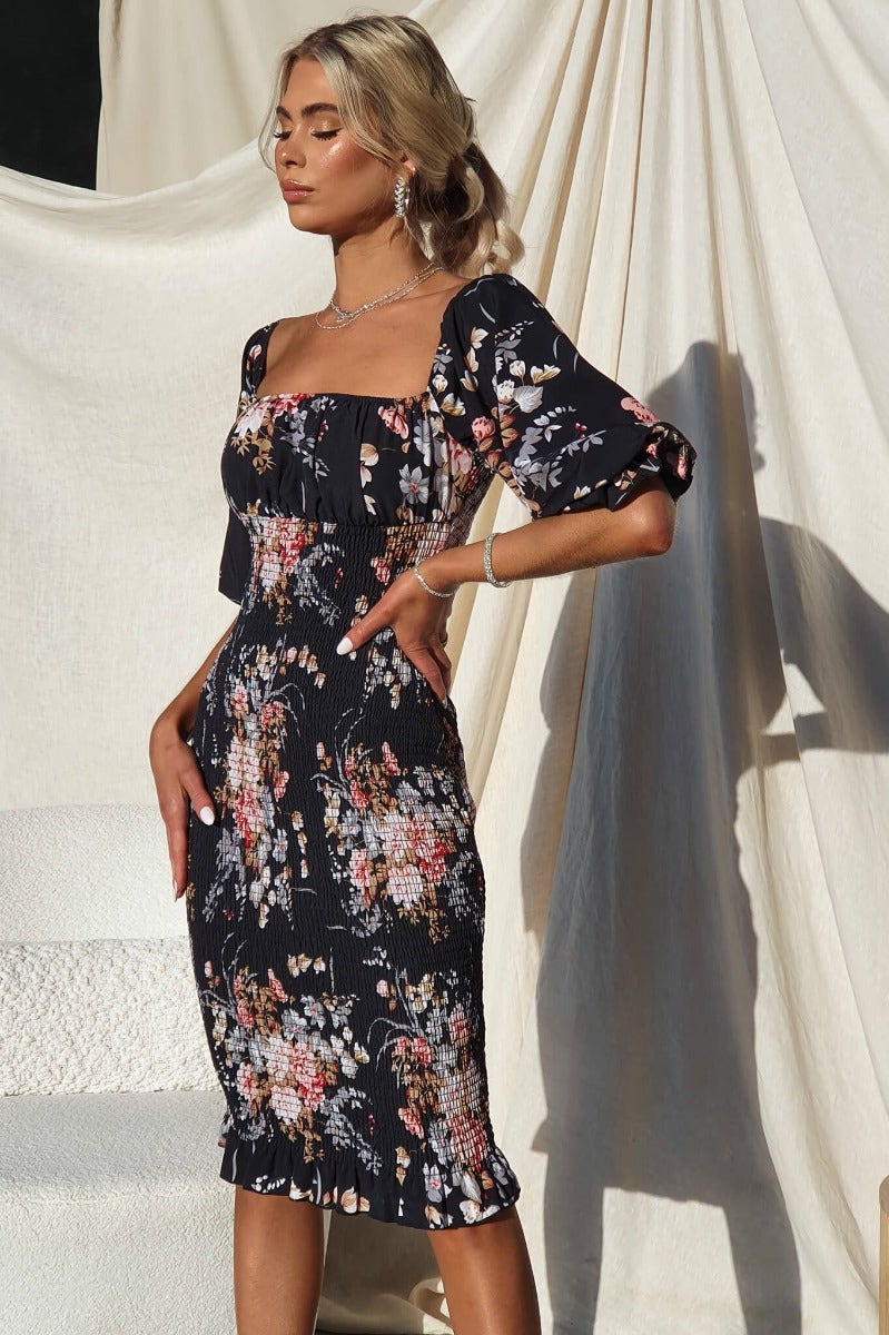 Arabella Midi Dress in floral design with elastic fittings, showcased on model against a textured backdrop.