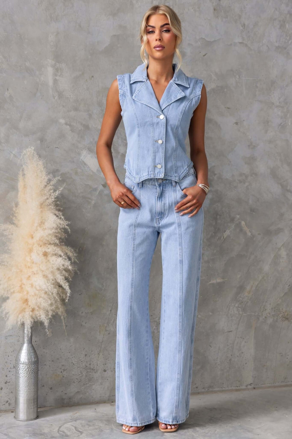 Model wearing Billie Jeans with a sleeveless denim top and wide-leg jeans, styled against a textured wall.