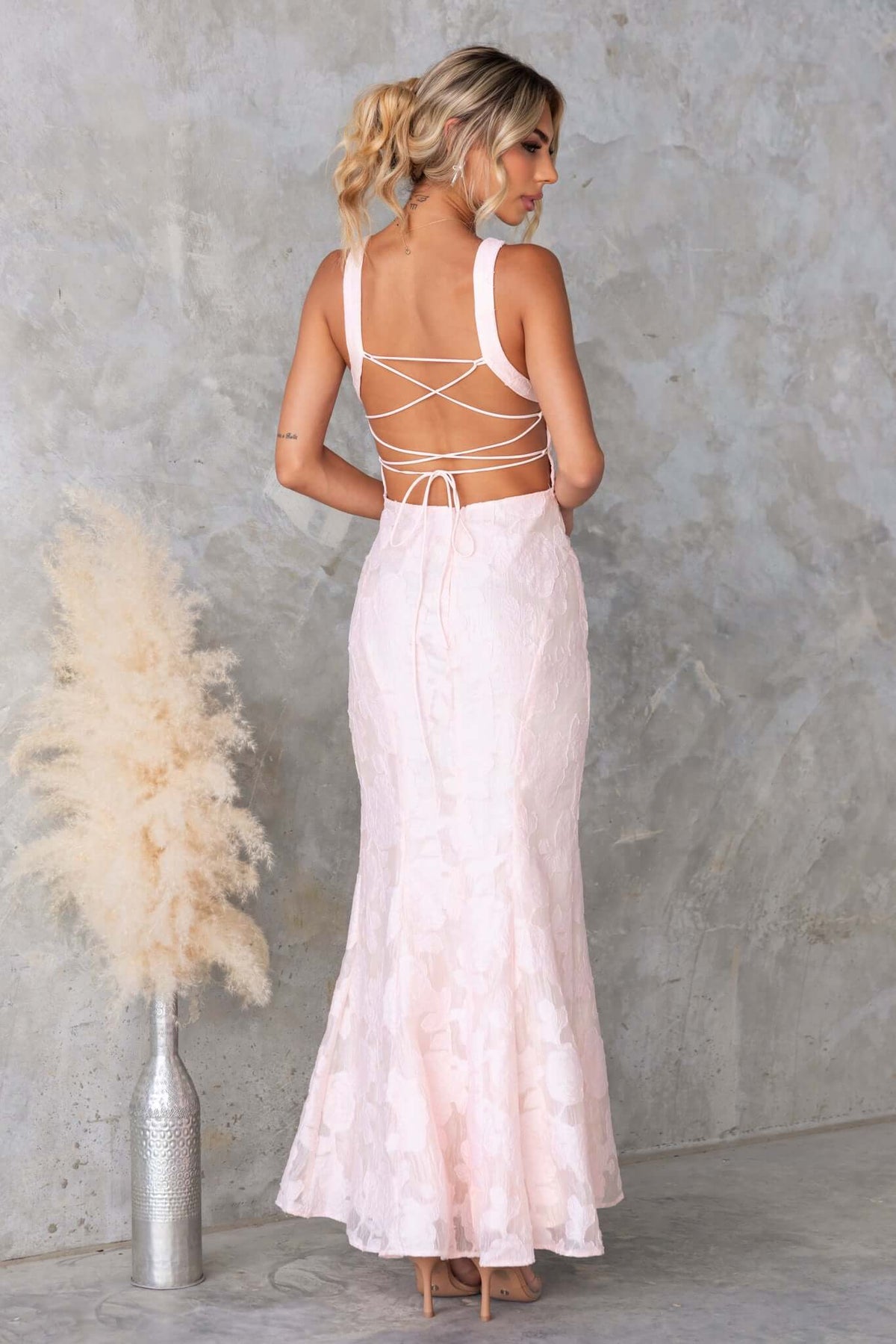 Back view of Remma Maxi Dress featuring a lace-up style and slight fishtail hem, styled with soft waves hair.