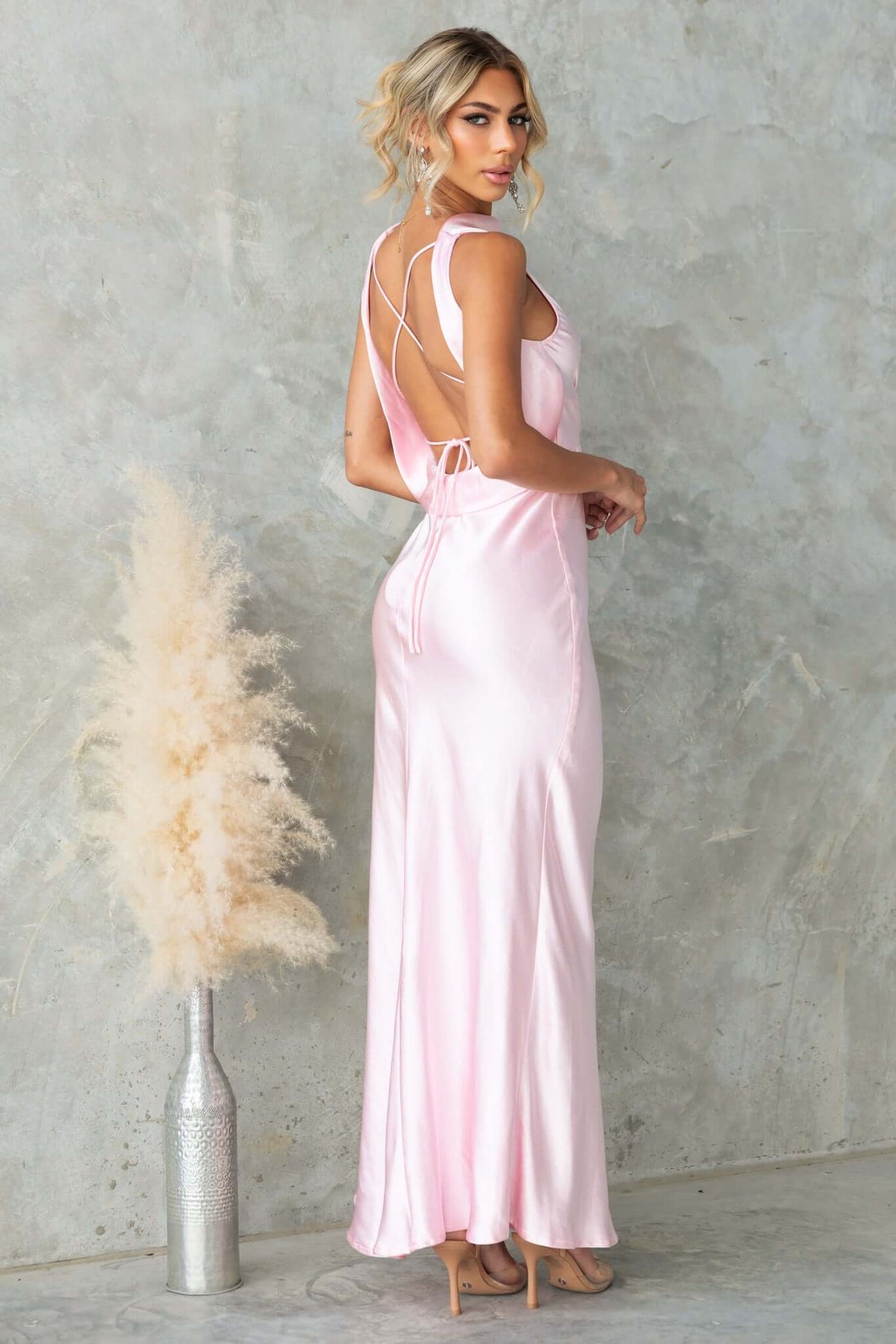 Model wearing a pink Silvia Maxi Dress with a boat neckline and stylish back tie detail.