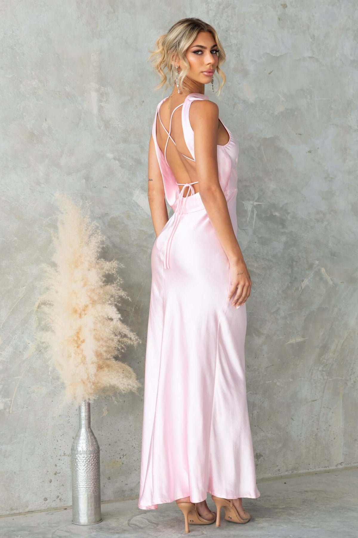 Silvia Maxi Dress in soft pink satin, featuring a boat neckline, draped back, and elegant tie detail.