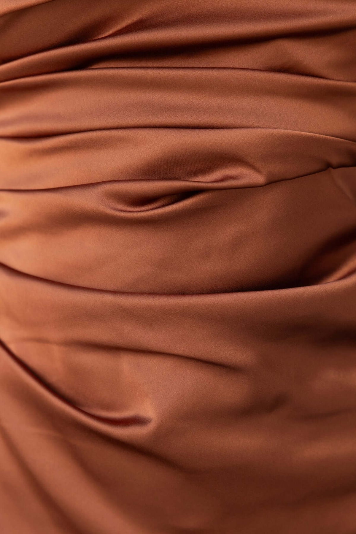 Close-up of luxurious satin fabric with elegant pleats, showcasing the texture of the Dimmi Maxi Dress by Amaroso Bridal.