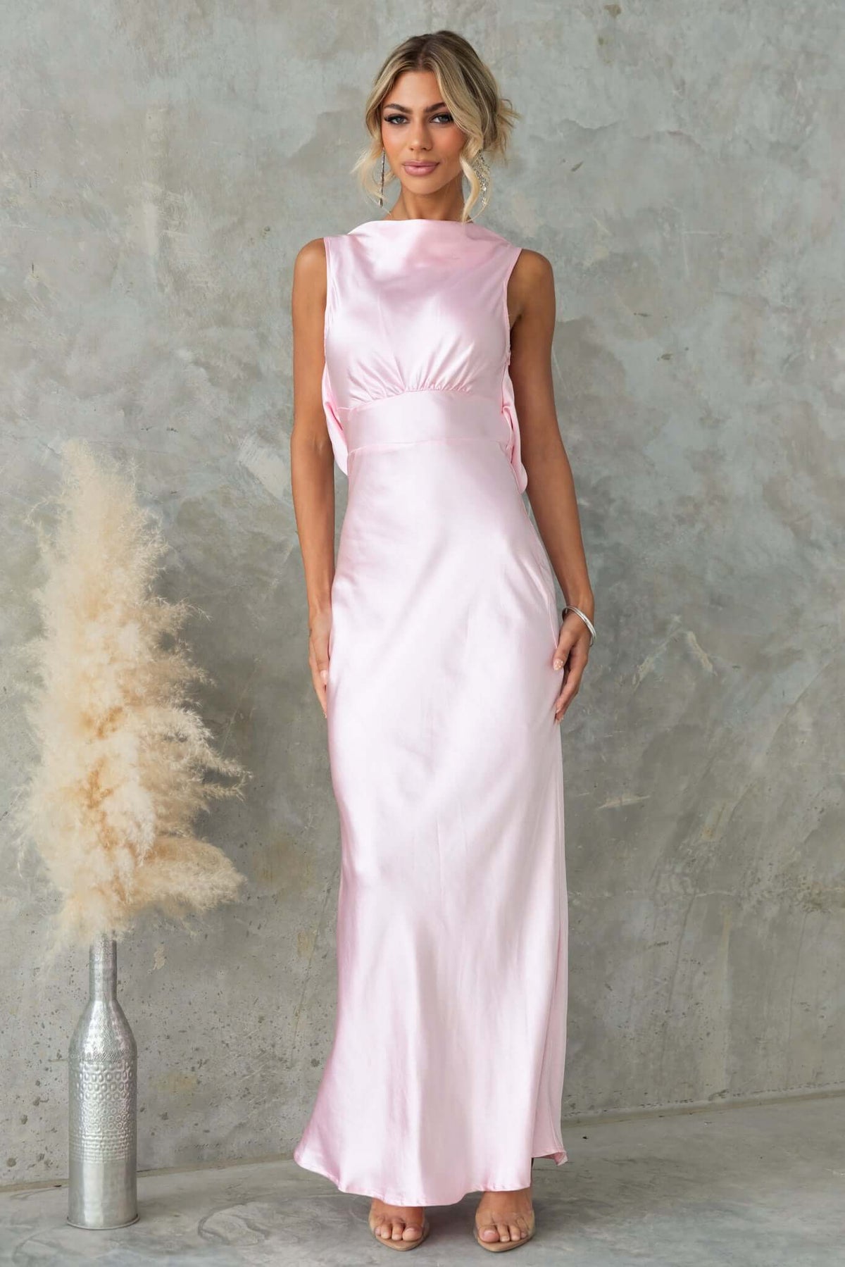 Model wearing a pink satin Silvia Maxi Dress featuring a boat neckline and draping detail.