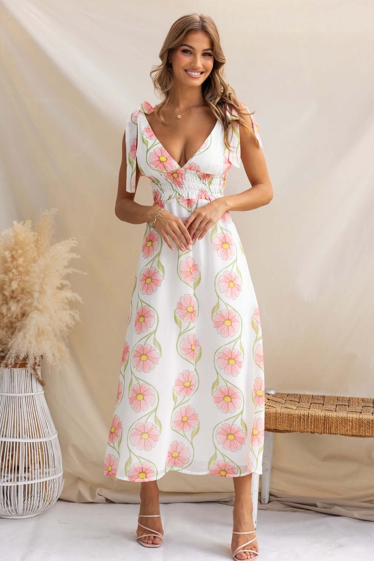 Woman wearing the Torrance Maxi Dress, featuring adjustable tie straps and floral print, styled against a soft background.