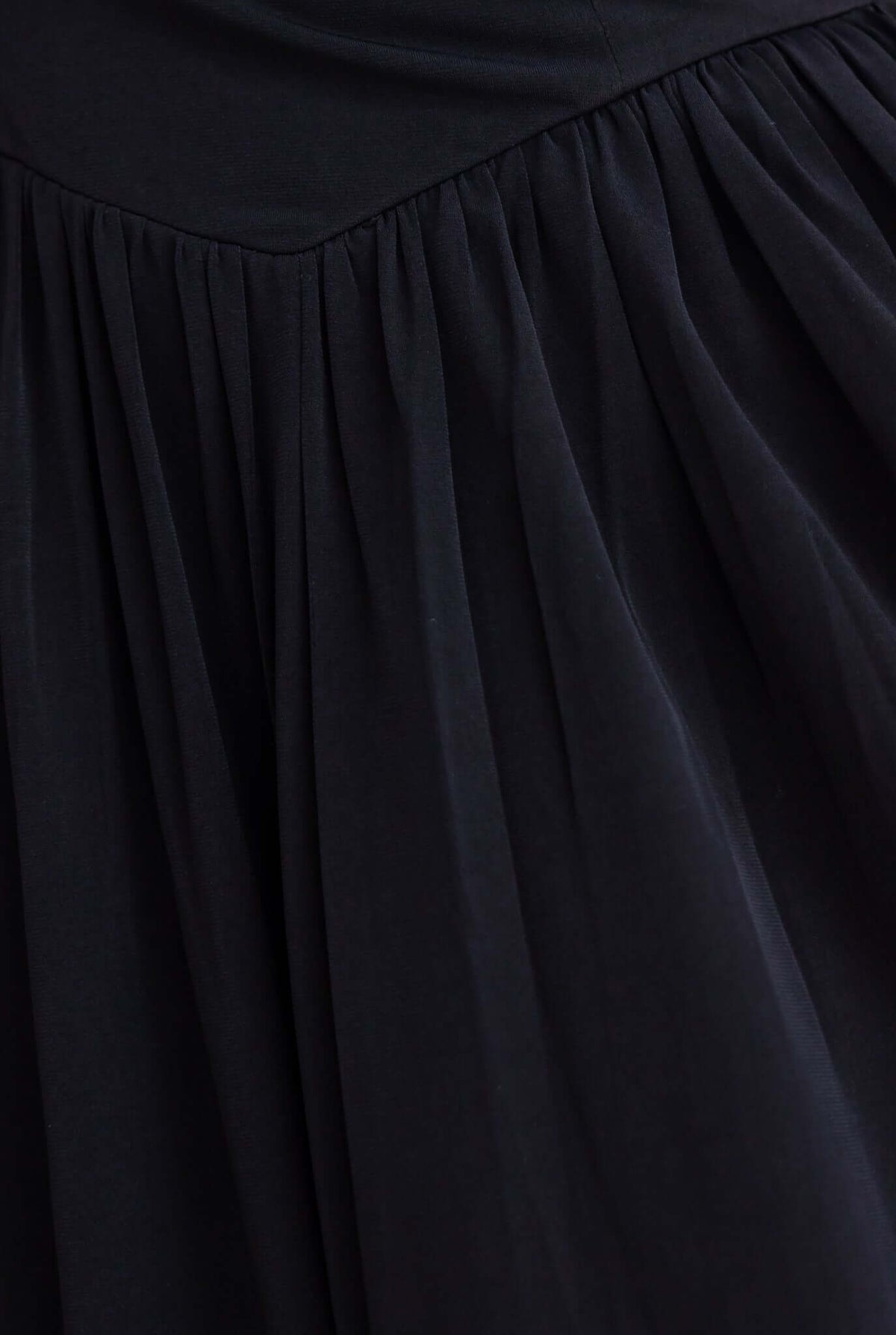 Close-up of the flowing black fabric of the Ulyssa Midi Dress, showcasing its gathered design and elegant texture.