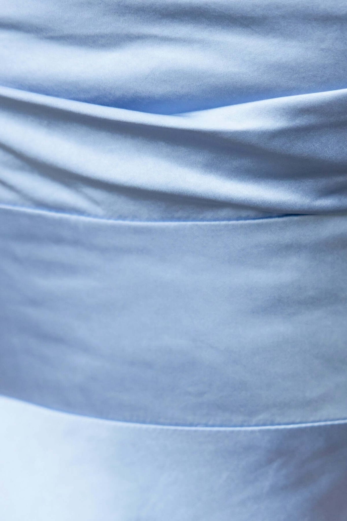 Close-up of the soft satin fabric and pleating detail of the Abigail Maxi Dress in light blue.