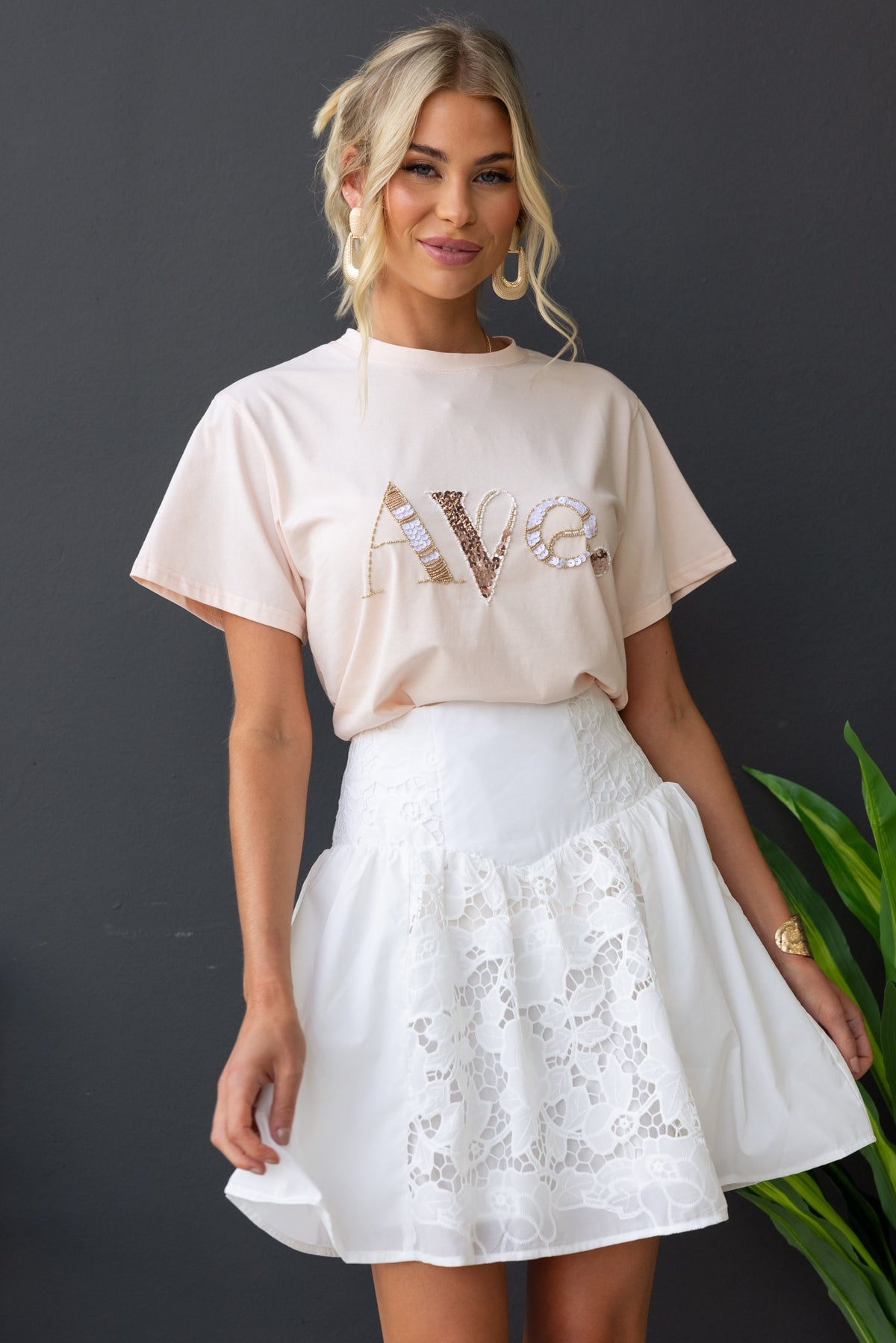 Model wearing a fancy cotton blend skirt with Anglasie detailing, styled with a casual pink graphic tee.