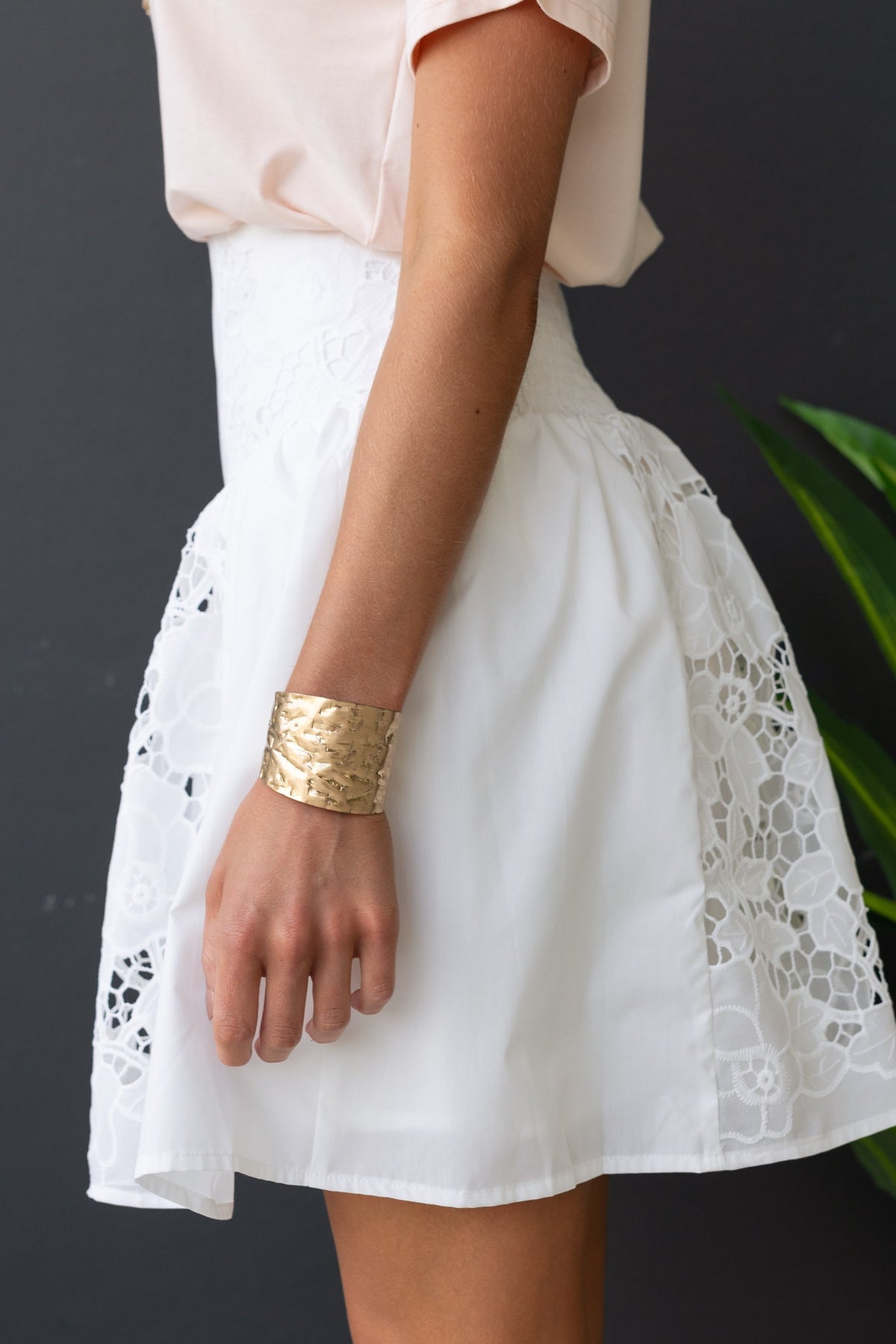 Model wearing a white cotton blend Fancy Skirt with Anglasie details, paired with a pink top and gold bracelet.