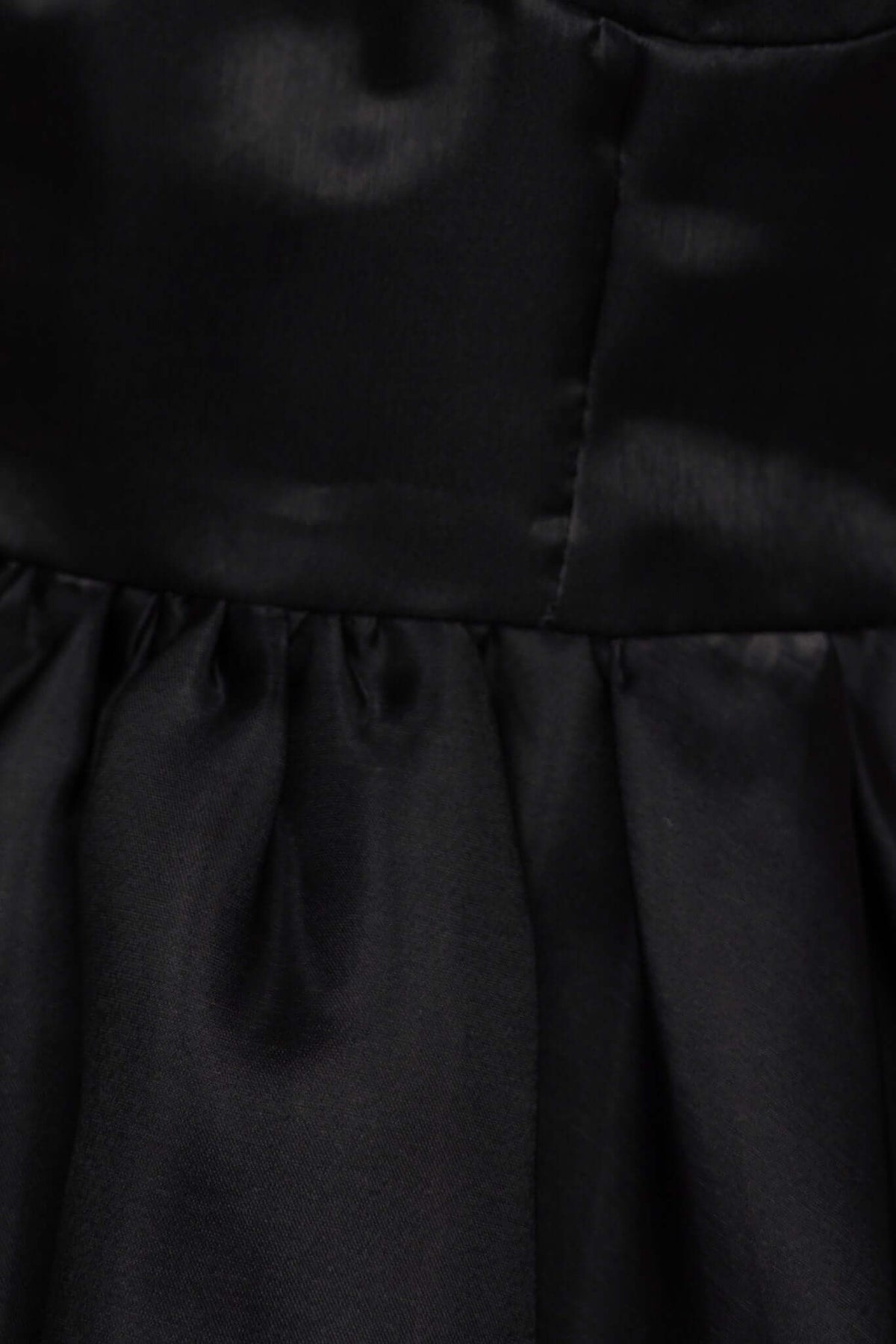Close-up of the Ermia Dress showing the luxurious black chiffon fabric with pleated details.