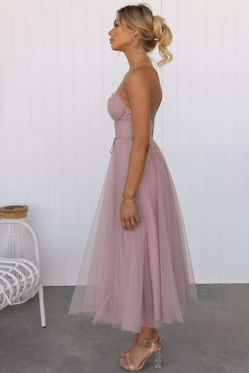 Side view of a model wearing the Florence Midi Dress in soft pink tulle, featuring cross-over straps and a removable tie.