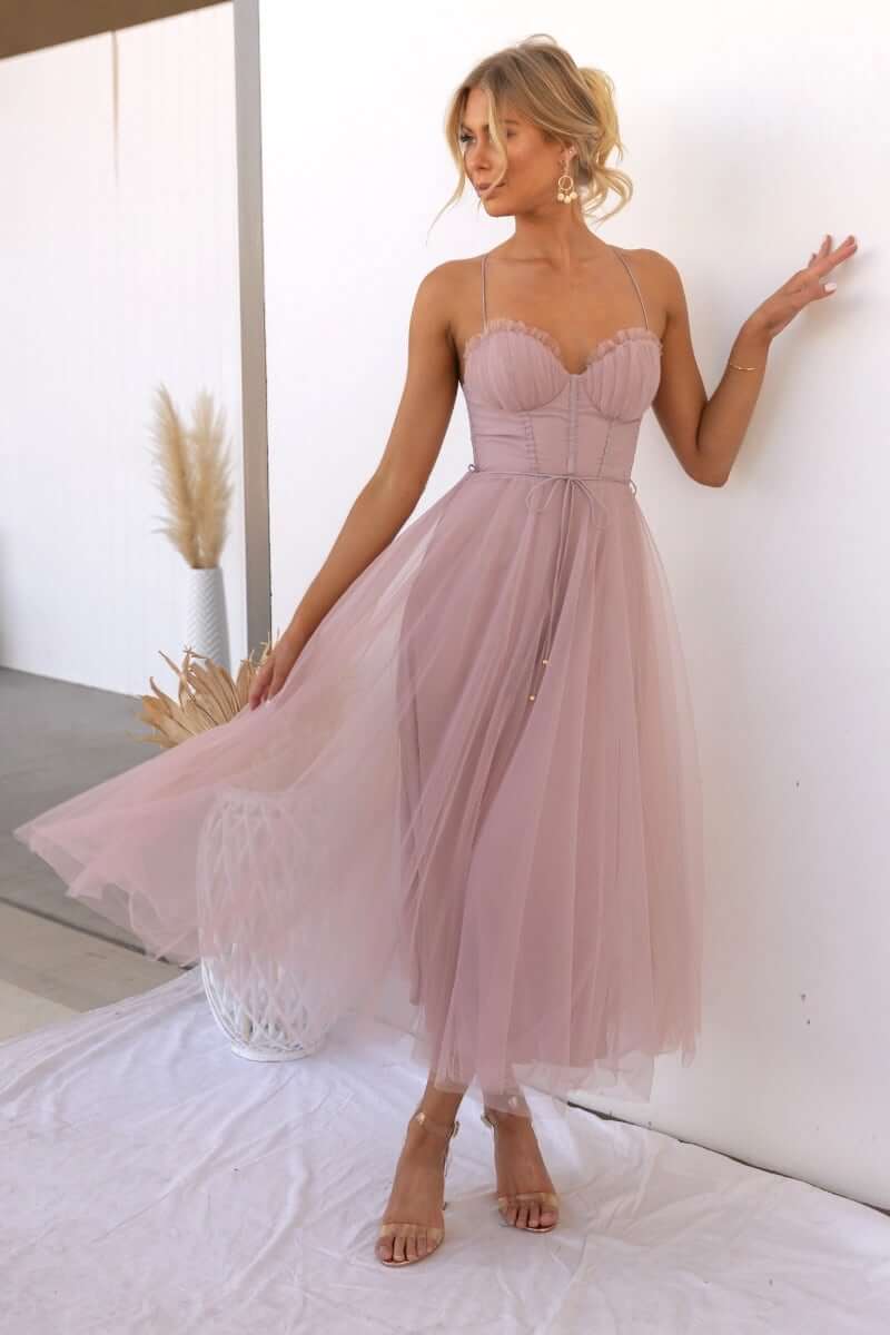 Model wearing the Florence Midi Dress, featuring tulle material, adjustable straps, and a removable tie in soft pink.