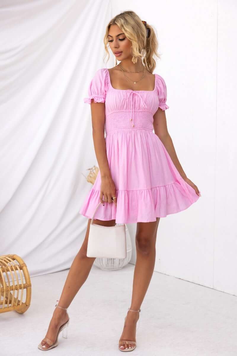 Love In Motion Dress in pink cotton blend, featuring round neckline, elastic waistband, and tie detail. Perfect for summer outings.