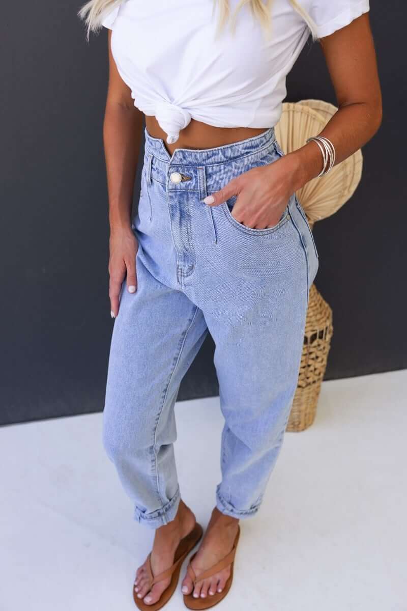 Model wearing Shaylan Mom Jeans with a mid-high waist, wide legs, and front pockets, styled with a white knotted t-shirt.