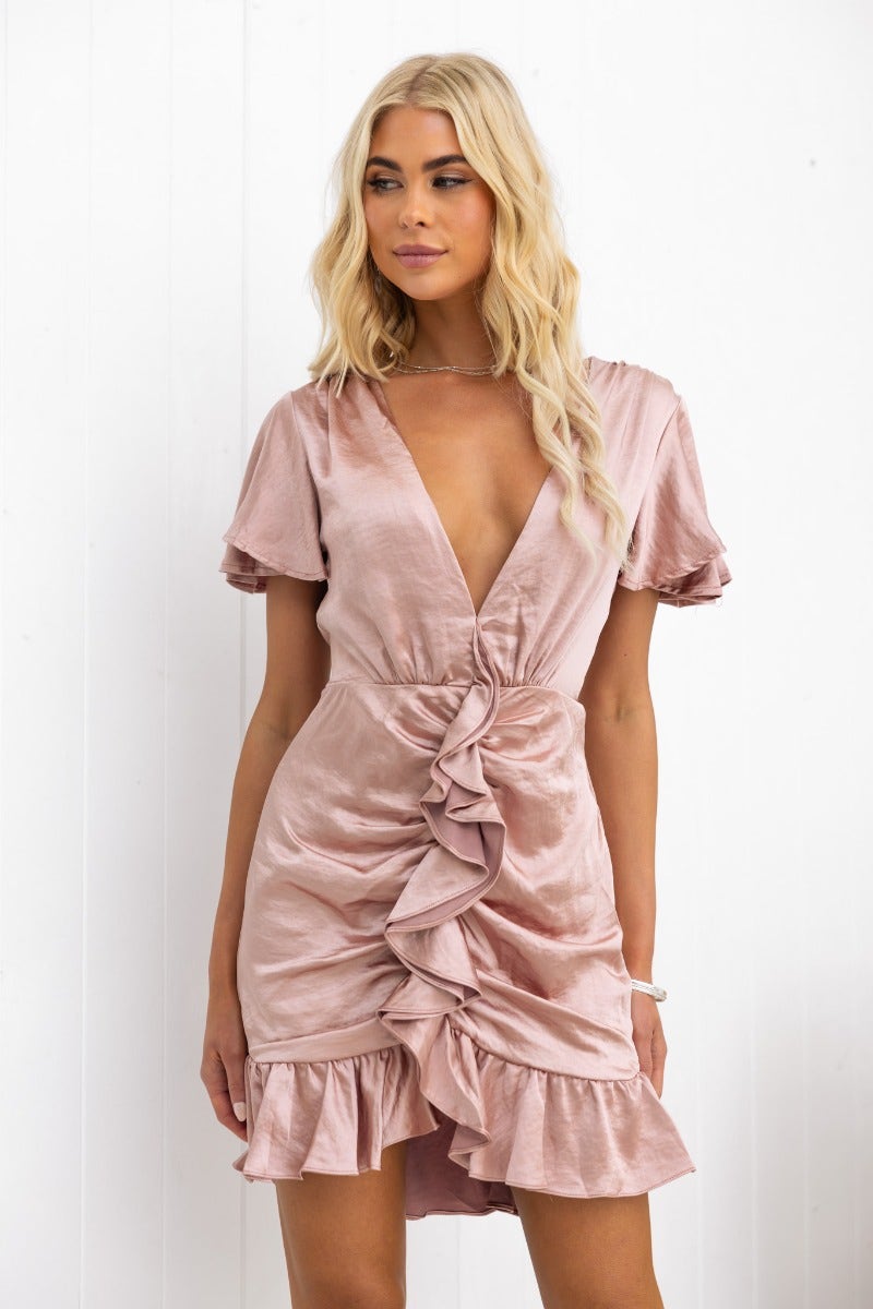 Fabiana Dress in blush satin with V-neckline and ruffle trim, featuring a fitted style and invisible back zip.