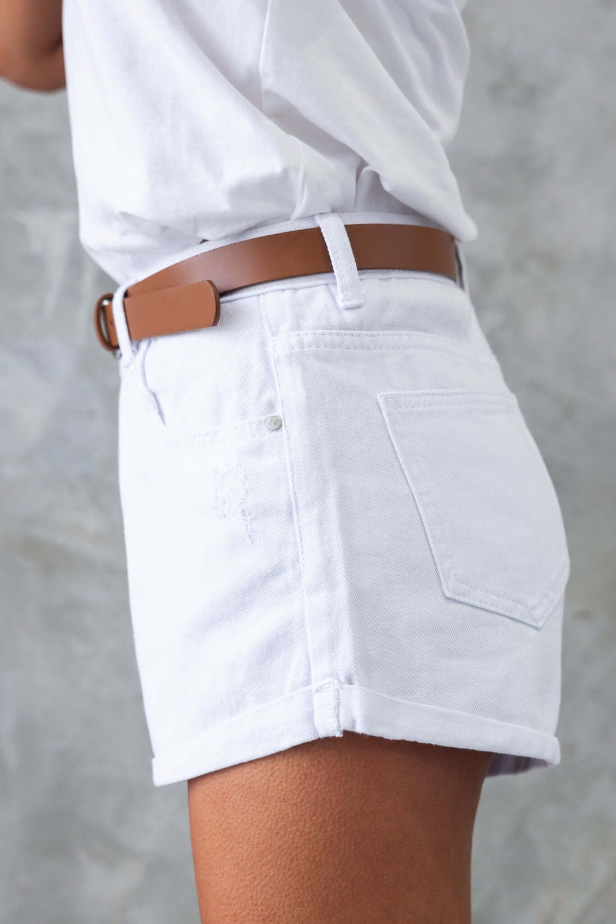 Side view of Kim Denim Shorts featuring front and back pockets, distressed detailing, and a mid-high waist fit.