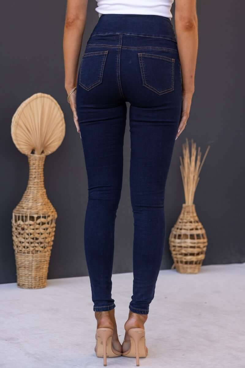 Back view of woman wearing dark navy Quiver jeans with mid-high waist and wide waistband style.
