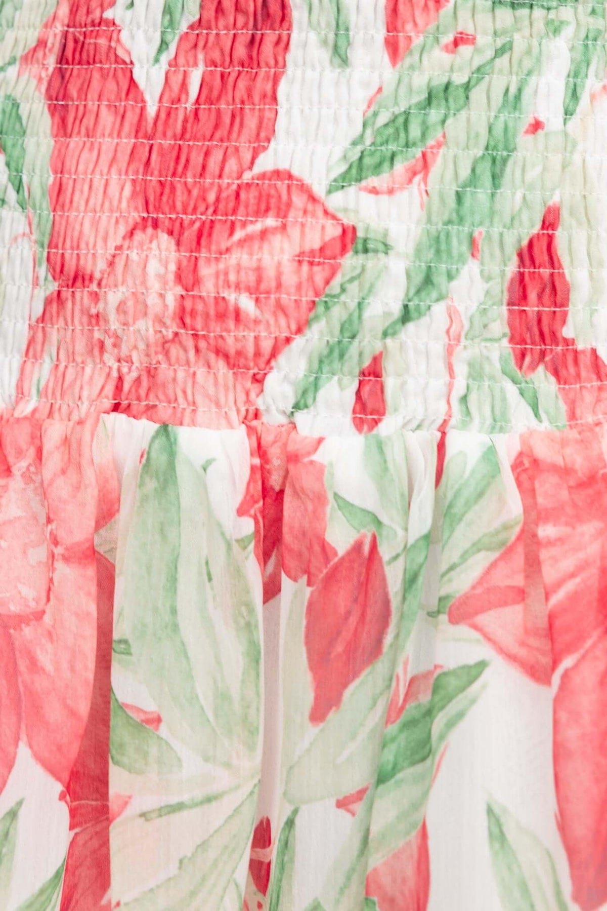 Close-up of floral patterned fabric in red and green, highlighting the smocked detail and lightweight design.