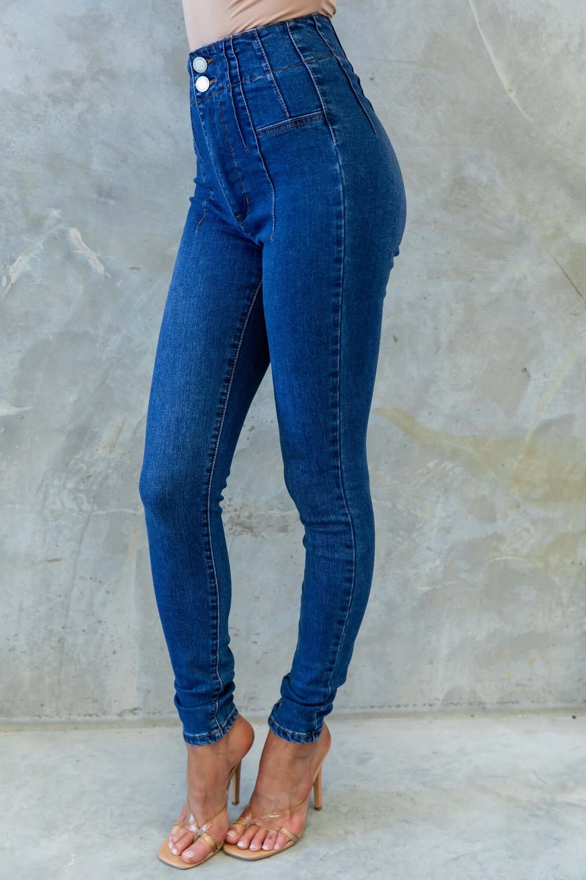 Okara Jeans in mid-high waist fit, featuring two-button closure and firm stretch denim, styled with high heels.