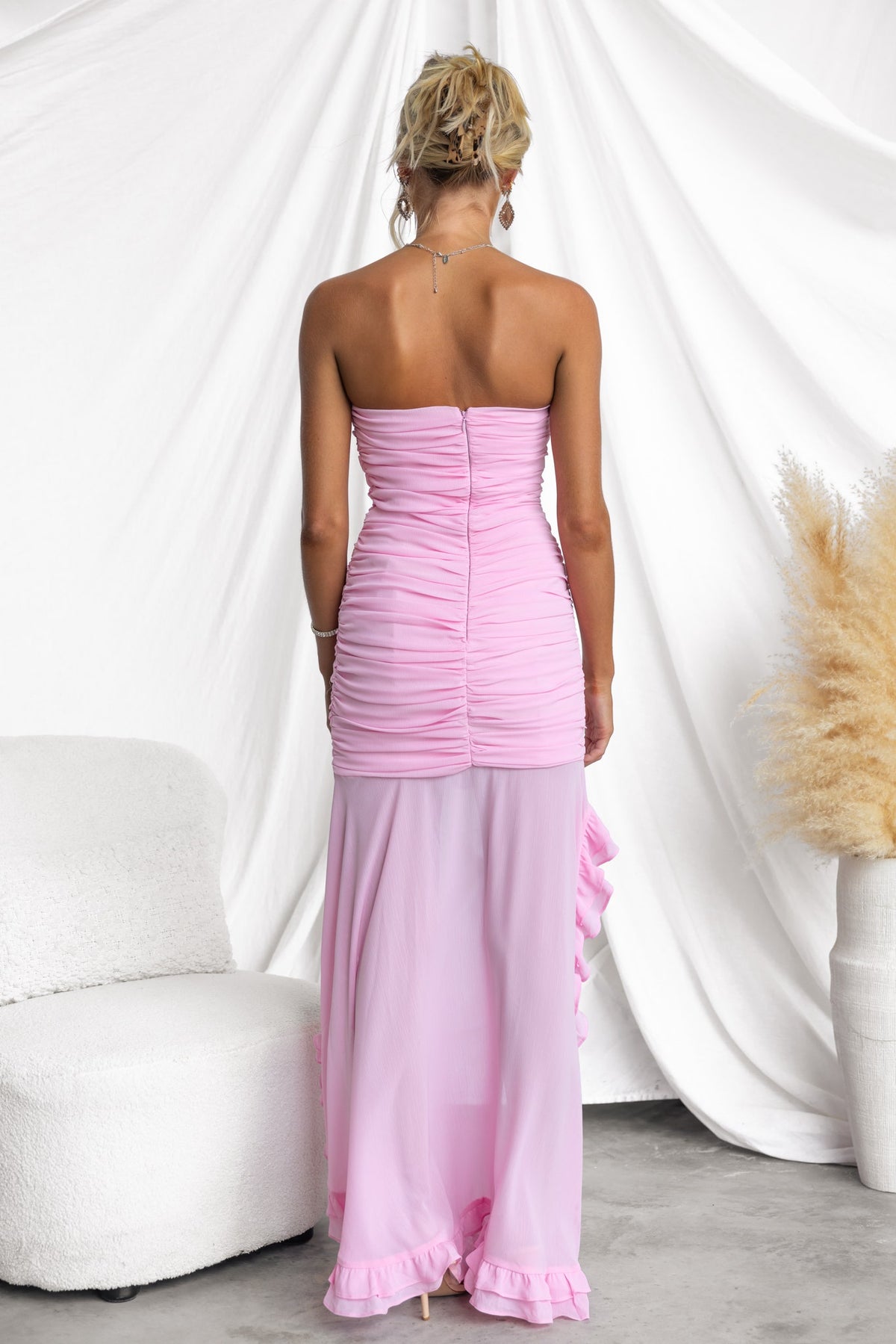 Back view of the pink Raylee Maxi Dress featuring ruching, a high-low hemline, and a strapless design.
