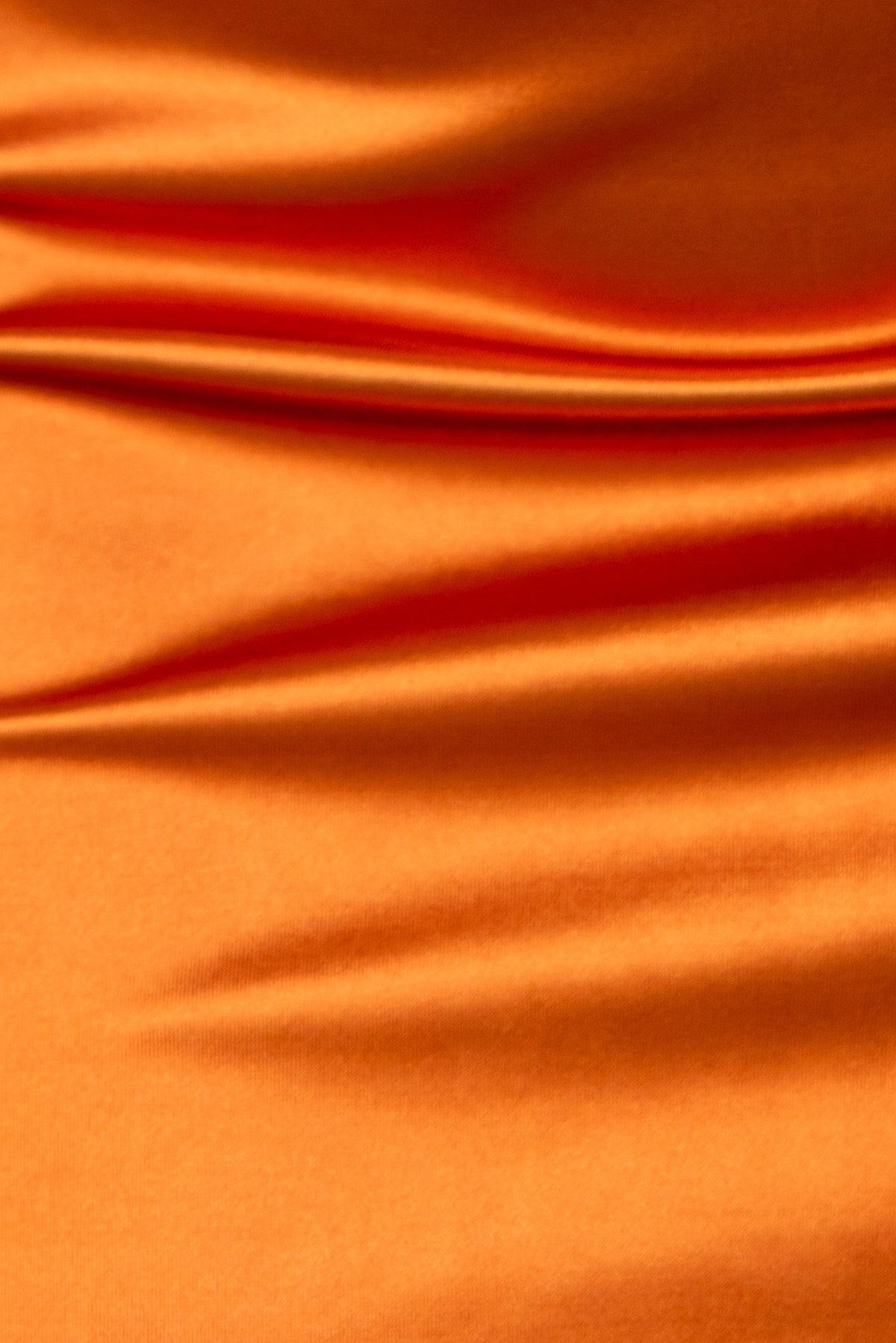 Close-up of smooth orange satin fabric showcasing its sheen and texture.