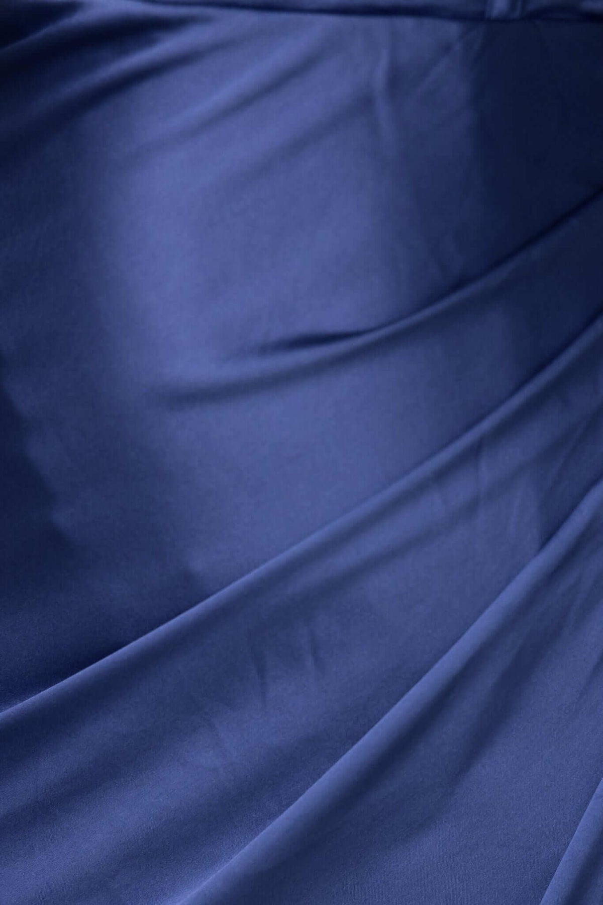 Close-up of the satin fabric detail of the Adele Maxi Dress featuring elegant draping in a deep navy color.