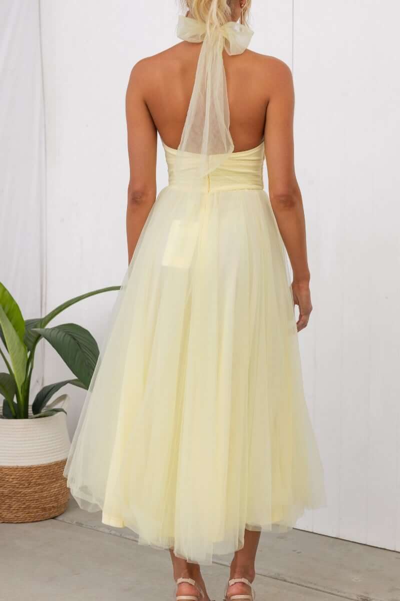 Back view of Love Lane Maxi Dress in soft yellow, featuring a tulle skirt and adjustable tie halter neckline.