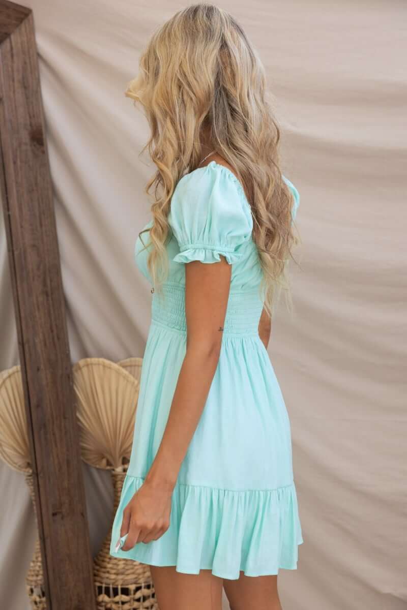 Model wearing the Love In Motion Dress, a mint green cotton blend dress with puff sleeves and a smocked bodice.