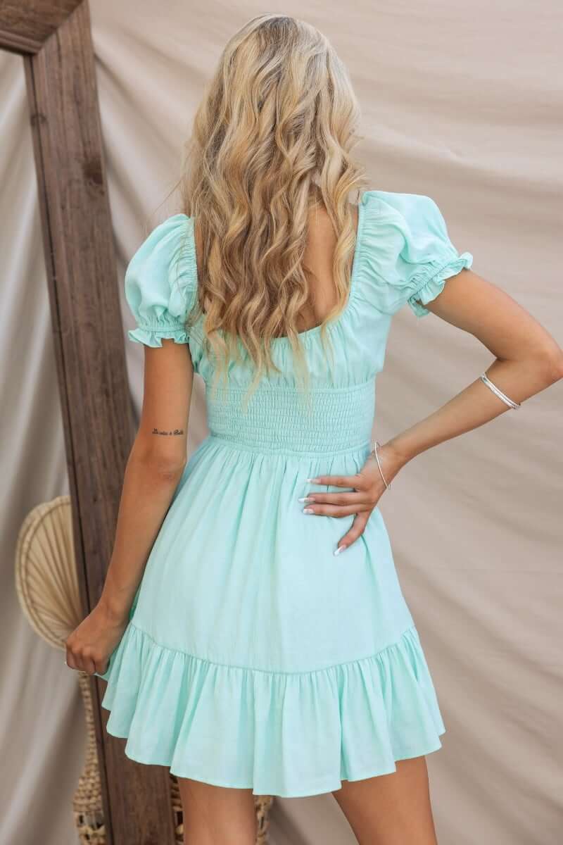 Back view of Love In Motion Dress, a mint green cotton blend dress with smocked bodice and ruffled hem.