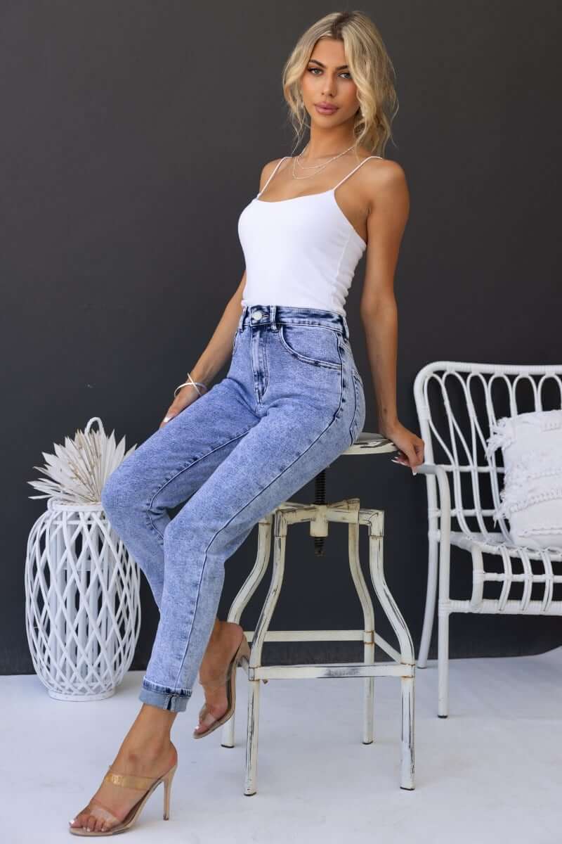 Model wearing Hush Mom Jeans with mid-high waist, light denim wash, styled with a white top and heels.