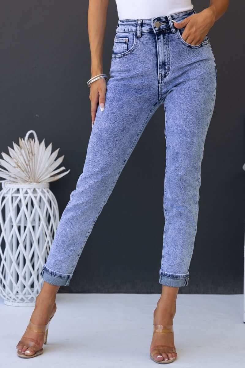 Hush Mom Jeans in light denim, mid-high waist fit, with pockets, styled with a white top and heels.