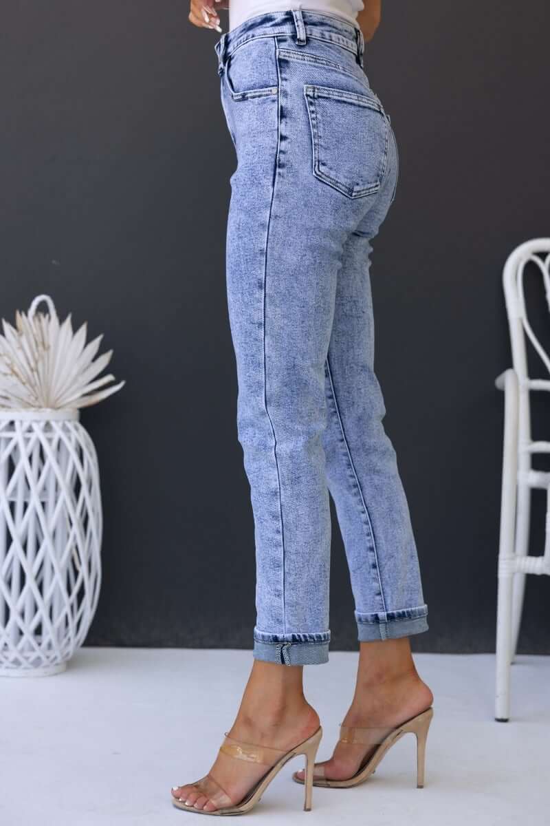 Side view of Hush Mom Jeans showcasing mid-high waist fit, firm stretch denim, and rolled cuffs, model paired with heels.