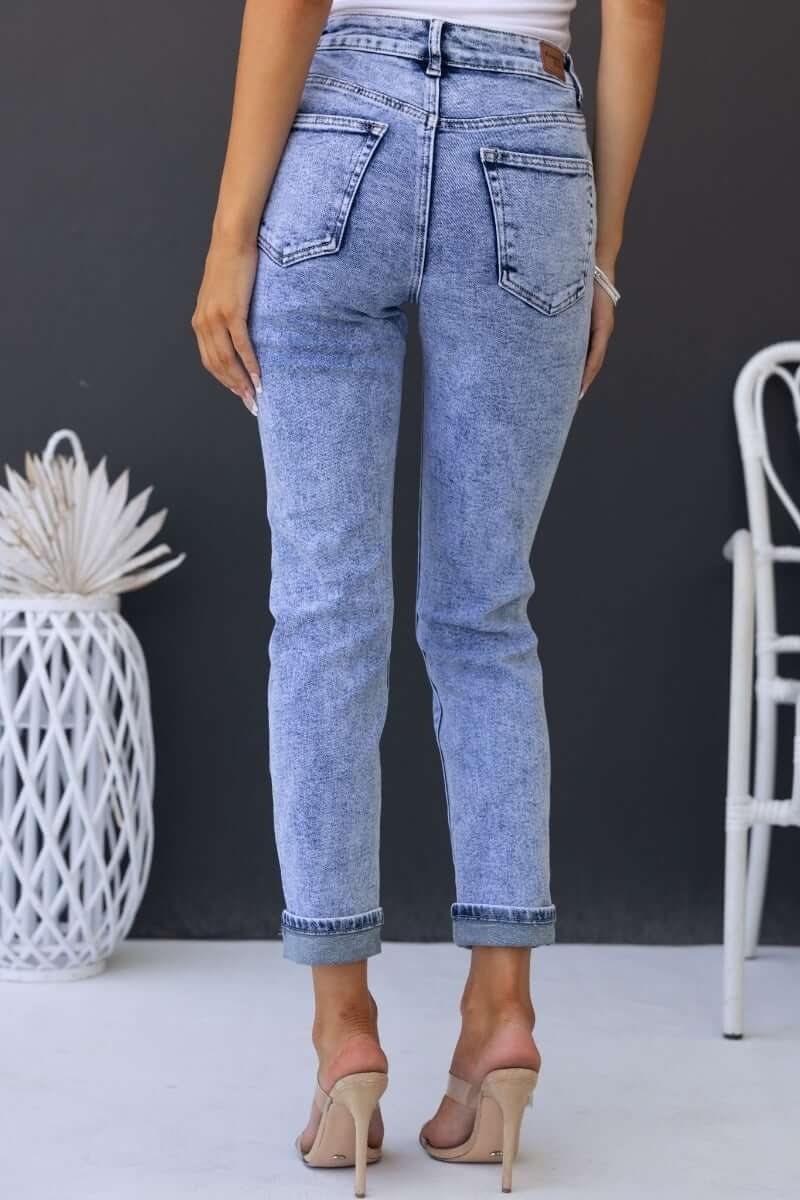 Back view of Hush Mom Jeans in light denim, featuring pockets and a tapered fit, ideal for casual outfits.