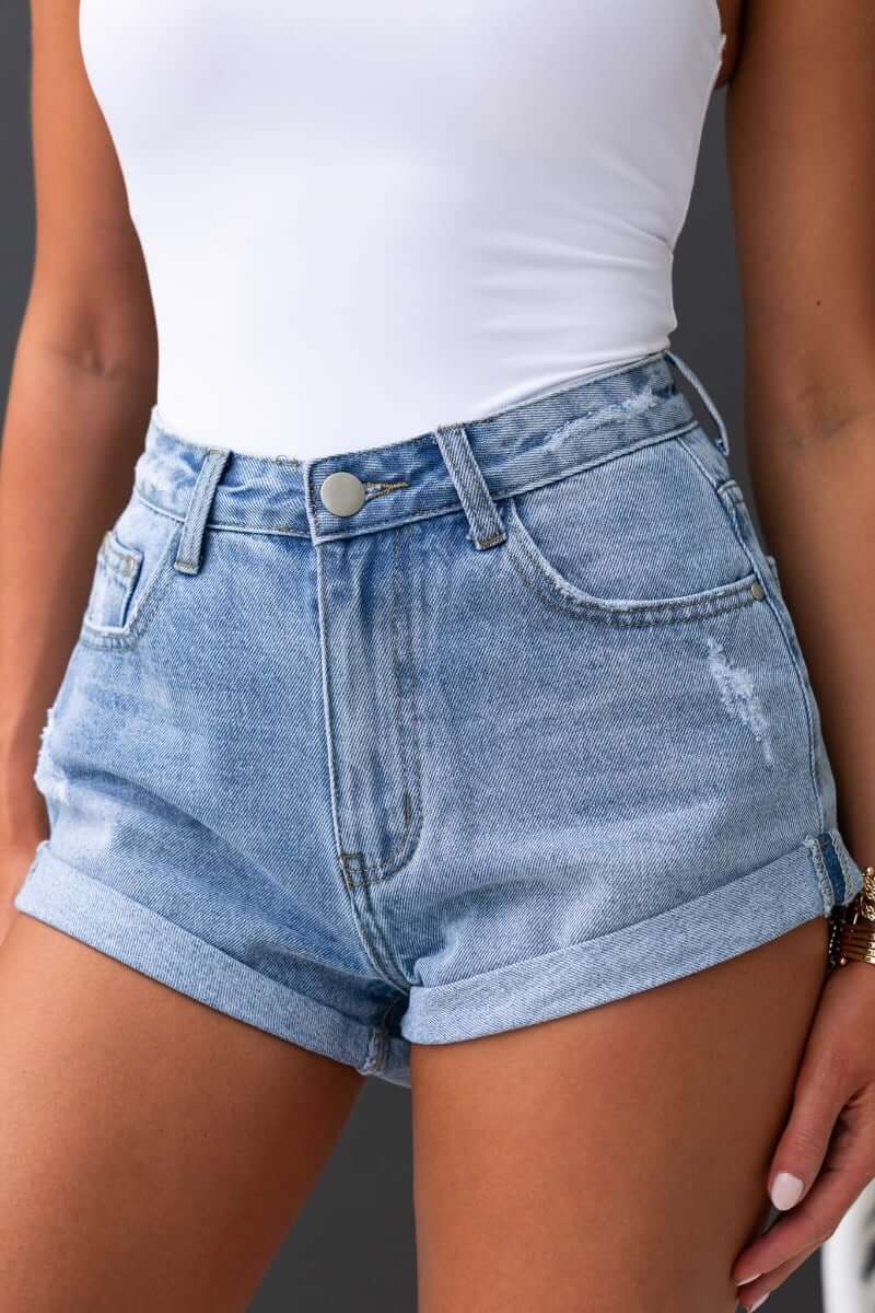 Kim Denim Shorts featuring a mid-high waist, front and back pockets, and distressed detailing in light blue denim.