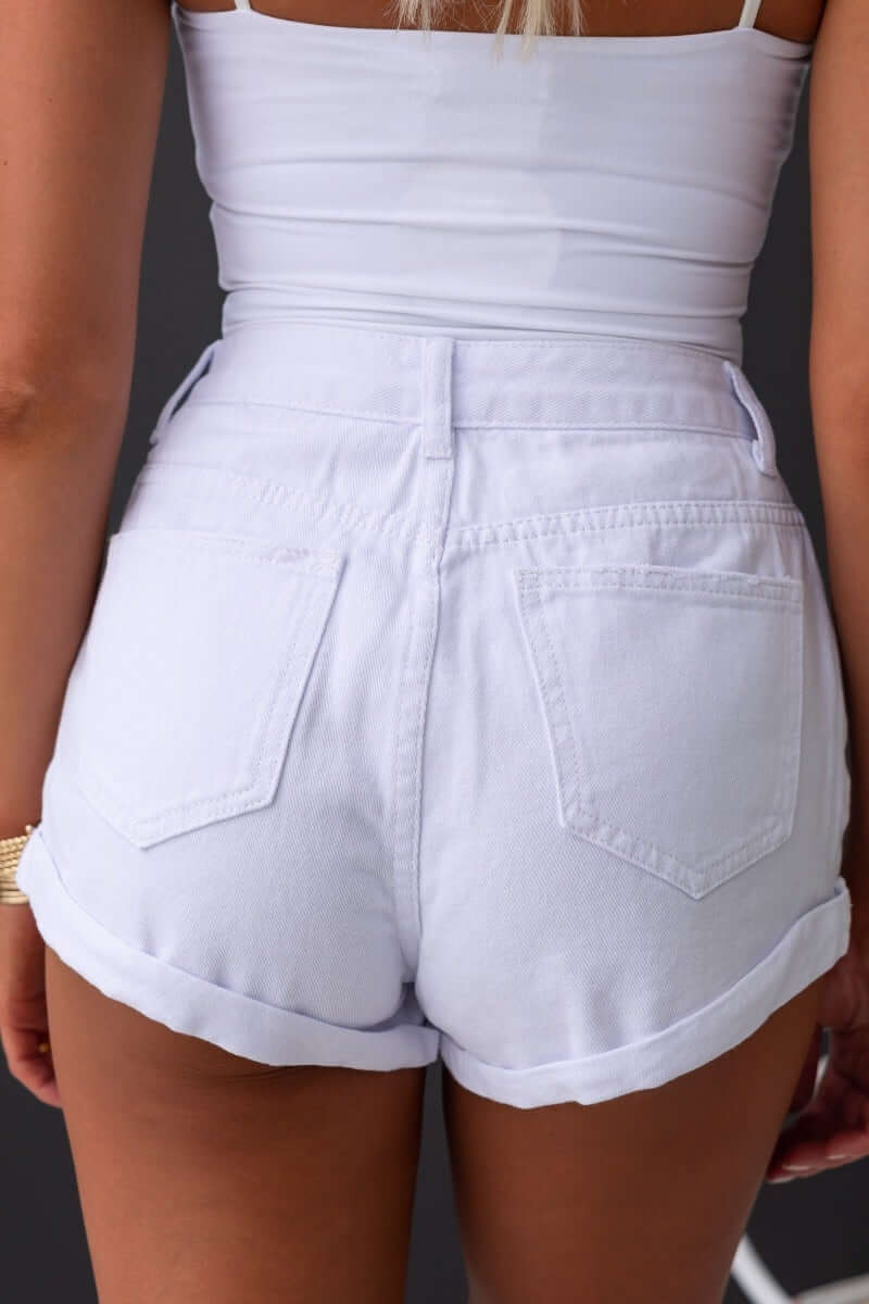 Back view of Kim Denim Shorts with mid-high waist, rolled hem, and pockets, showcasing distressed detailing.