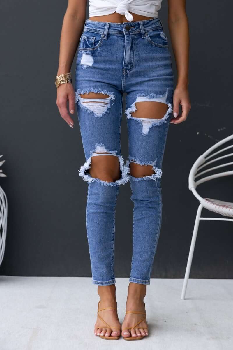 Fletcher jeans featuring a mid-high waist with distressed rips, front and back pockets, and a skinny fit.