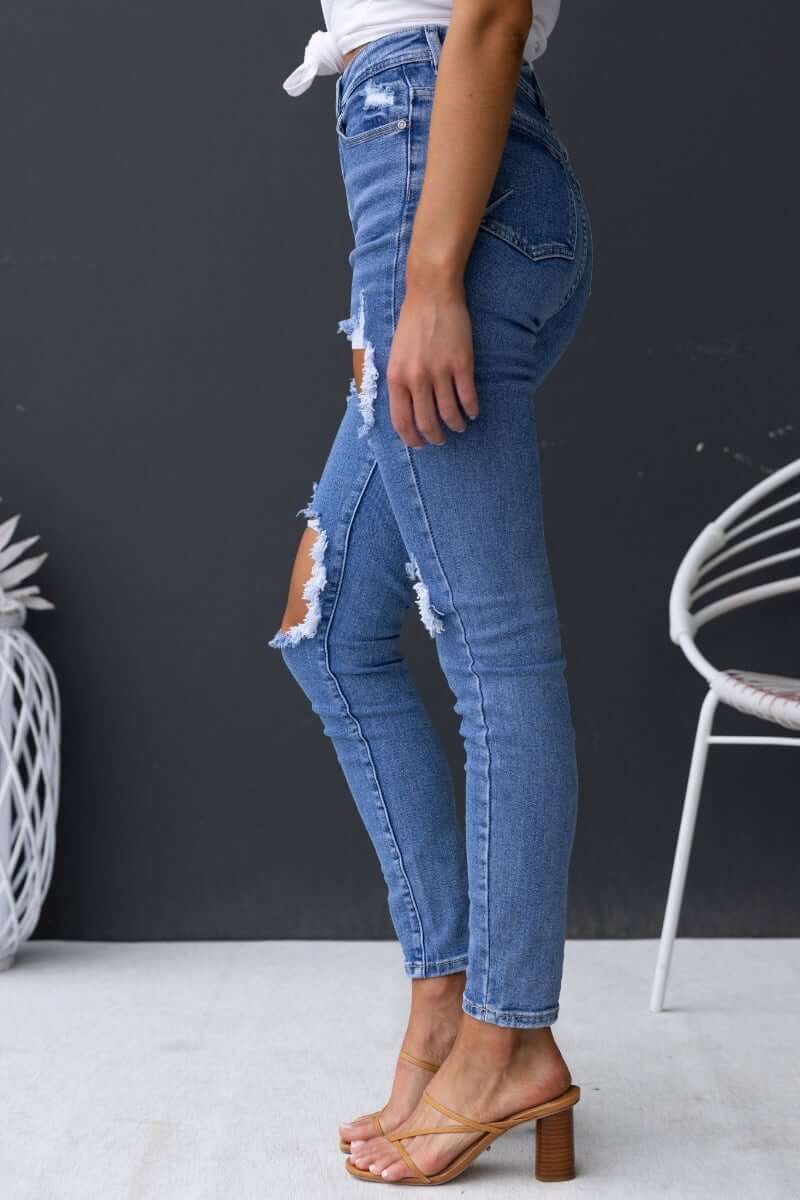 Fletcher Jeans featuring mid-high waist, distressed rips, and front & back pockets, styled with a fitted look.