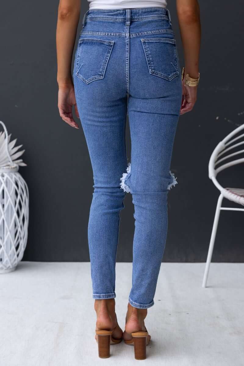 Fletcher jeans featuring a mid-high waist, distressed rips, and a skinny fit, showcased from the back view.