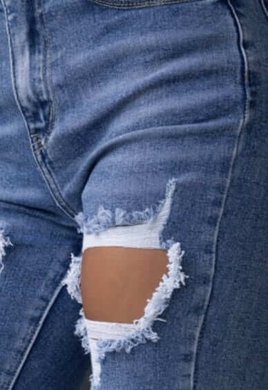 Close-up of Fletcher Jeans featuring distressed rips and mid-high waist fit in soft denim with stretch.