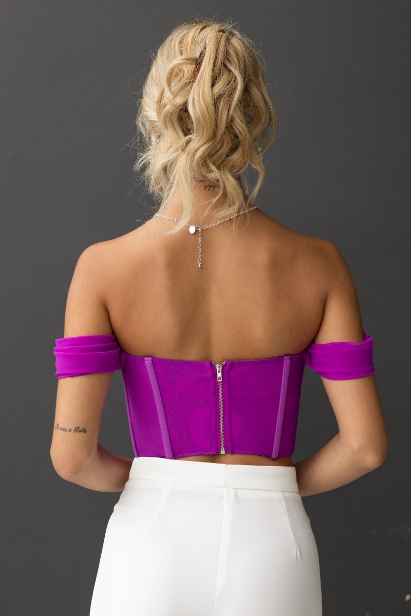 Model wearing Taria Top, a purple off-shoulder corset top with back zip and boning details.