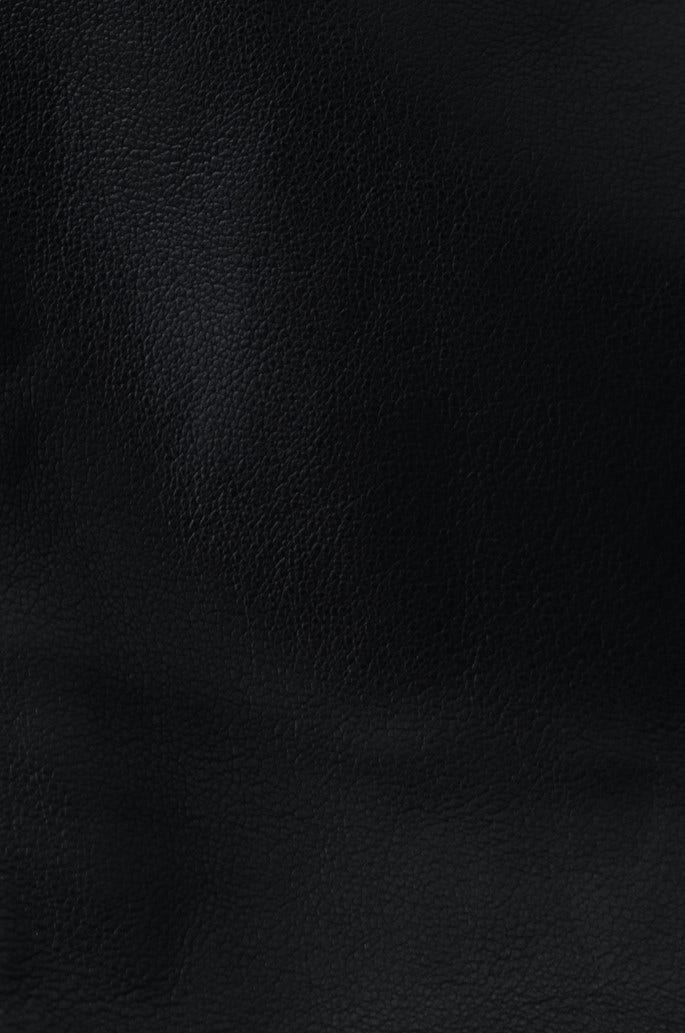 Close-up of black faux leather texture, showcasing the sleek finish perfect for stylish pants.