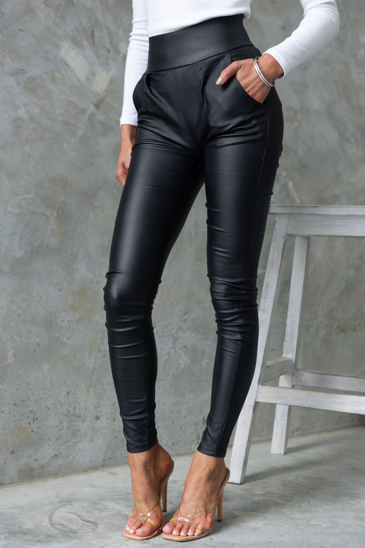 Reece Pants: Black faux leather high-mid waist pants with front pockets and zip back, styled with a fitted top.