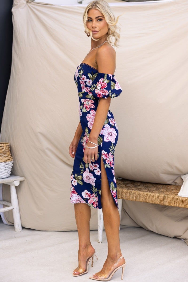 Feminine off-shoulder navy floral midi dress with side split, worn elegantly by a model.