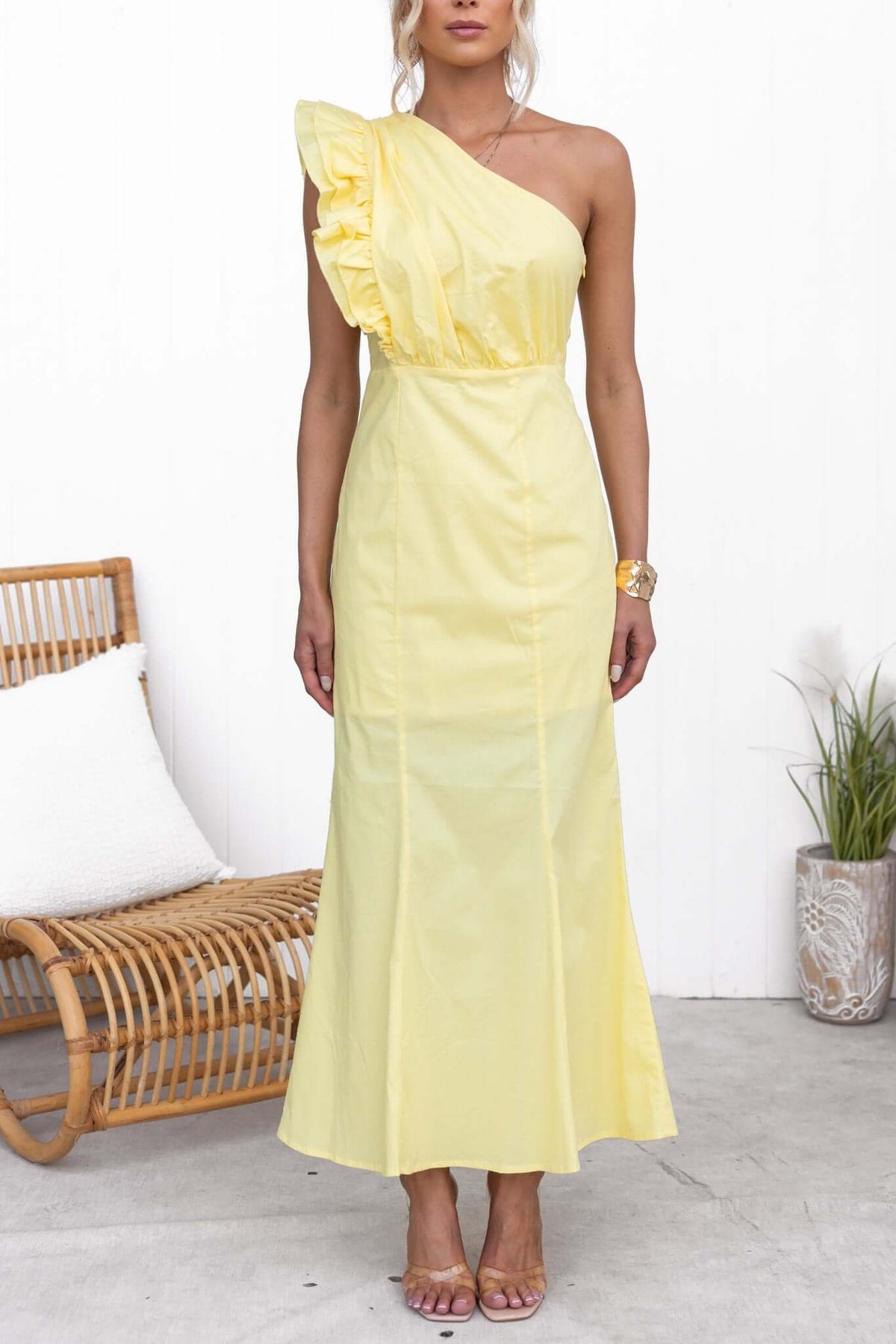 Stylish model wearing a yellow Hopewell Maxi Dress with a one-shoulder neckline and ruffle detail, perfect for summer events.