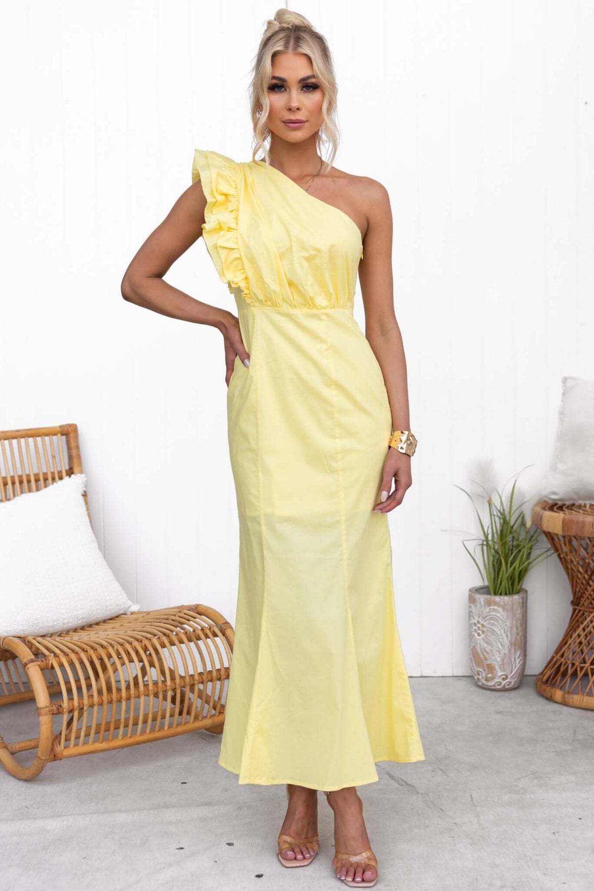 Model wearing a yellow Hopewell Maxi Dress with one-shoulder design and ruffle detail in a stylish setting.