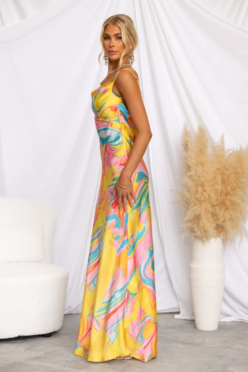 Satin Visionary Maxi Dress in vibrant yellow with colorful marbling design, featuring cowl neckline and adjustable straps.