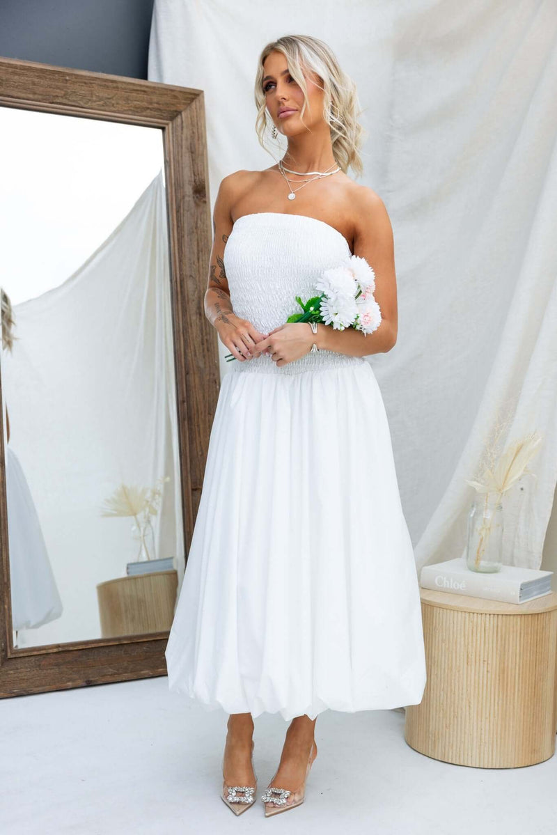 Model wearing the Cadro Midi Dress, a strapless white dress, showcasing an elastic bodice and a lined skirt.