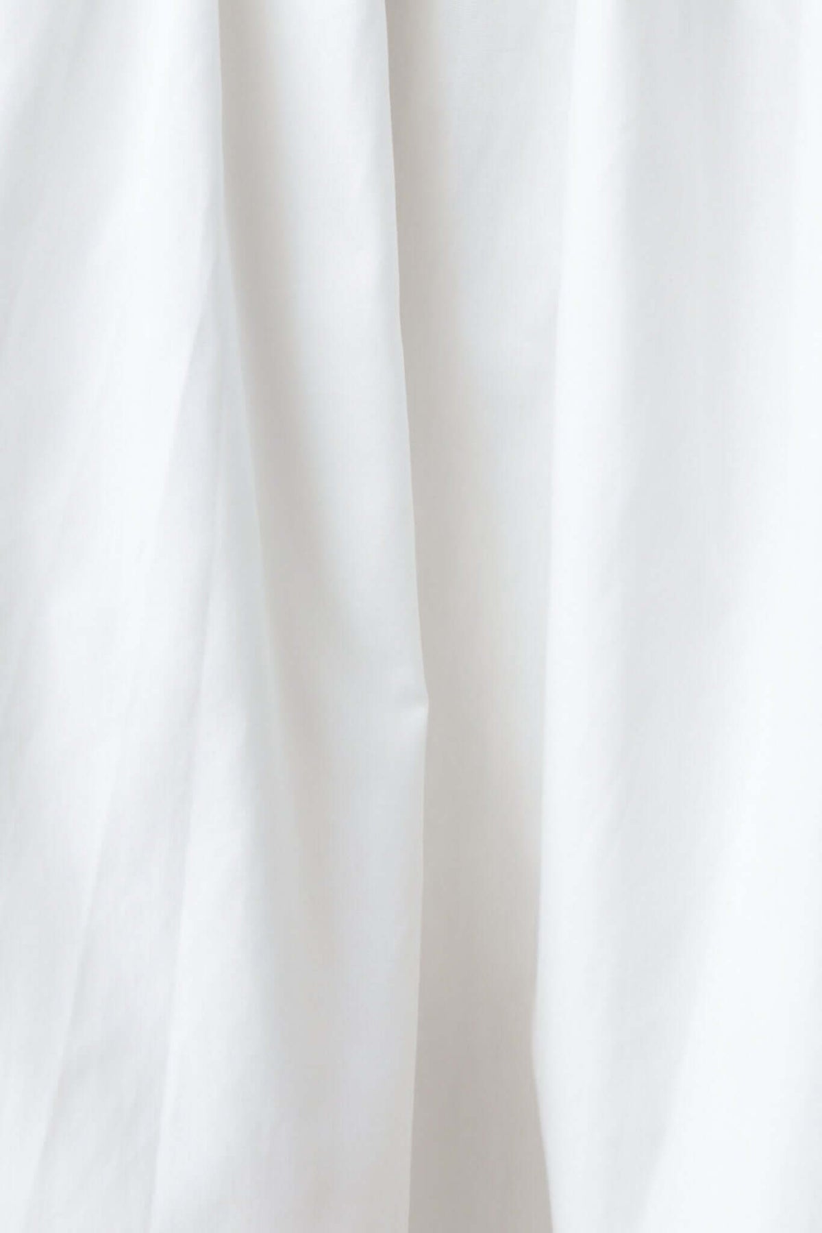 Close-up of the smooth, white fabric of the Trieste dress, showcasing its soft texture and elegant drape.