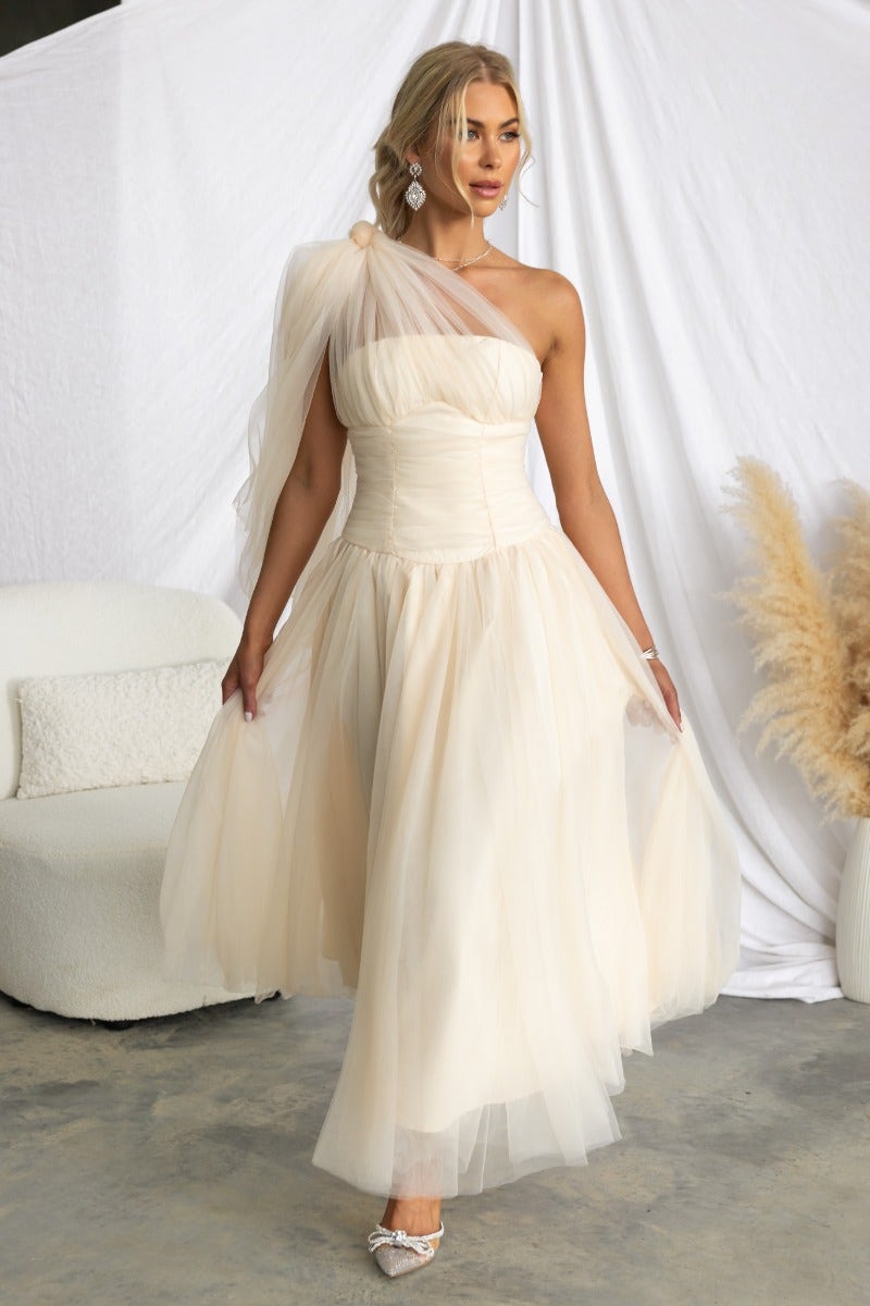 Elegant Belle Maxi Dress in ivory with tulle overlay and one-shoulder design, styled with earrings.