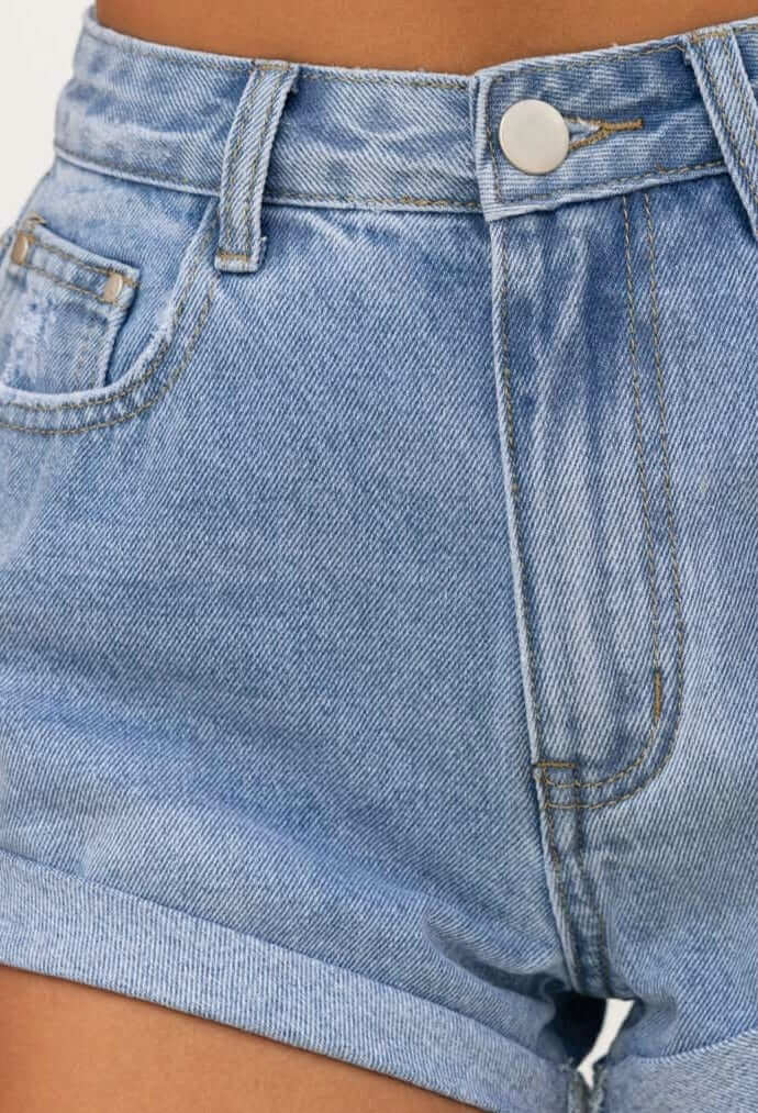 Close-up of Kim Denim Shorts featuring a mid-high waist, distressed detailing, and rolled hem in light blue wash.